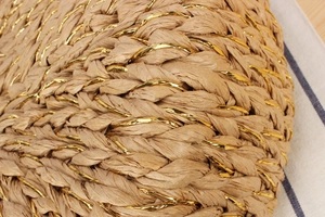 Close-up of hand-woven straw texture with elegant gold threads on the beach bag