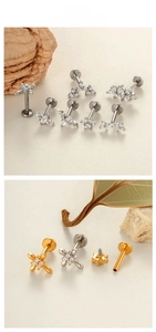 Macro d'un piercing en acier avec étoiles en cristal, plumes et croix dorées