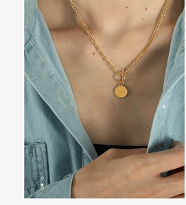 Detail of gold OT buckle necklace with Beloved engraved round pendant on denim shirt