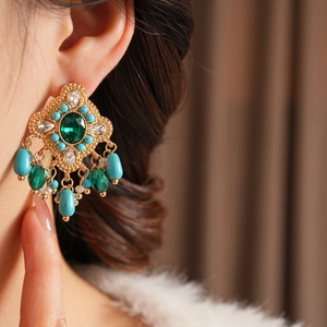 Gros plan sur boucle d'oreille vintage avec cristaux verts et perles turquoise sur mannequin