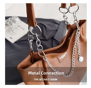 Detailed close-up of the silver chain strap and metal hardware on a brown leather tote bag