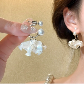 Dettaglio di eleganti orecchini con perle e fiori mostrati indossati dal modello