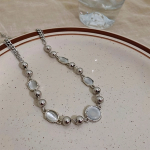 Close-up of silver cat eye stone necklace with metal beads on a ceramic plate