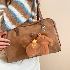 Ciondolo a forma di cavallo di peluche marrone appeso a una borsa abbinata in una scena calda