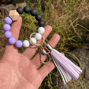 Macro view of purple and white silicone bead wristlet with wooden bead and lavender tassel