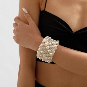 Detail view of a multi-row elastic pearl beaded wide bracelet on model wrist