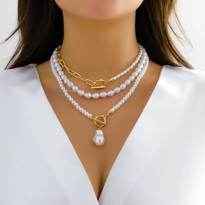 Close-up of layered faux pearl necklace with gold OT buckle and baroque heart pendant