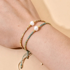 Close-up of bohemian handmade beaded bracelets with white pearls and adjustable cords