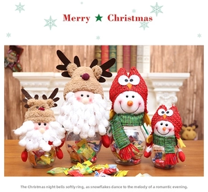 Detail of Christmas candy jars featuring plush reindeer and snowman caps on wood table