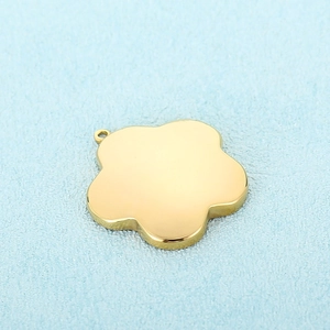 Polished gold stainless steel flower pendant necklace accessory on a light blue surface