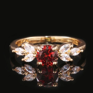 Macro shot of gold ring featuring a central red gem and white marquise-cut stones