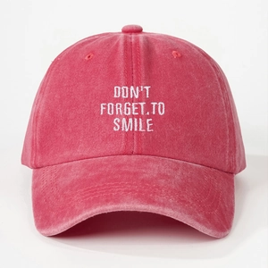 Detailansicht der weißen Stickerei DON'T FORGET TO SMILE auf der roten gewaschenen Baumwollkappe