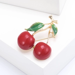 Elegant cherry brooch with bright red fruits and green leaves on a white podium