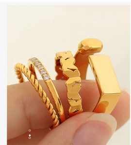 Detailed macro view of four stackable gold rings featuring rhinestone and floral patterns
