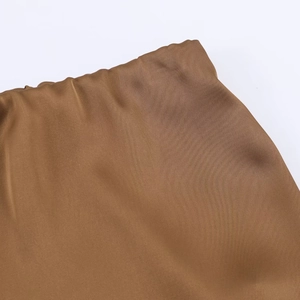Vue macro du tissu satiné bronze de la jupe midi montrant la texture lisse et brillante