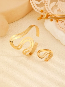 Detalle de conjunto de brazalete y anillo geométrico dorado ajustable sobre base texturizada