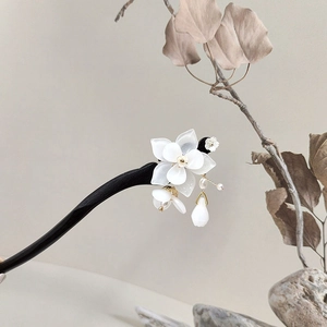 Detail of white magnolia flower wooden hair pin with elegant tassels and beads