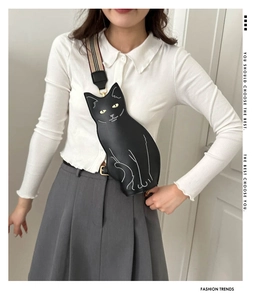 Detail of cute cat-shaped chest bag with yellow eyes and striped fabric strap