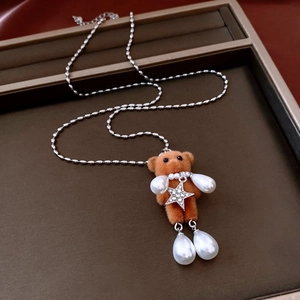 Detail of flocked brown bear pendant with pearl accents on a brown leather tray