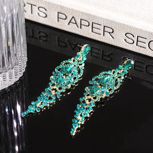 Macro view of emerald green teardrop tassel earrings with sparkling rhinestones and gold finish