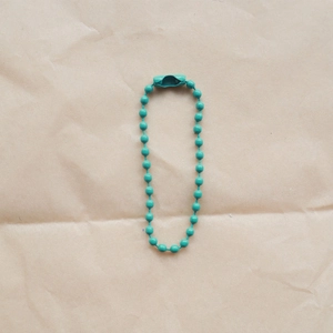 Detailed view of turquoise bead chain with connector on rustic kraft paper background