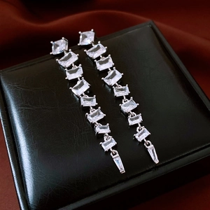 Détail macro de boucles d'oreilles pampilles en argent avec zircons sur velours