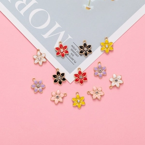 Colorful enamel flower charms with rhinestones for DIY necklaces and bracelets on pink background