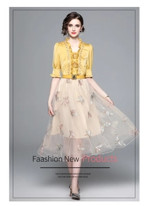 Detail of yellow satin blouse with ruffles and beige tulle skirt with butterfly embroidery