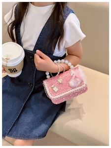 Detail of pink sequin girl's handbag with pearl handle and swan feather decoration