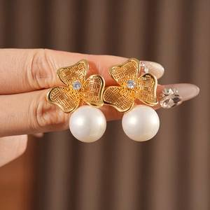Macro detail of S925 silver stamp on gold clover earrings with pearl and zircon