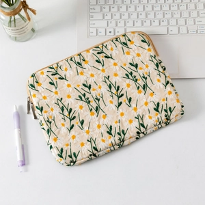 Detailed embroidery of white daisies and dual metal zippers on a quilted laptop sleeve