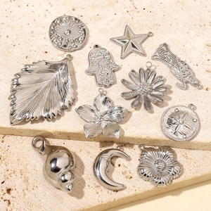 Silver stainless steel charms in leaf, star and moon shapes on beige stone background