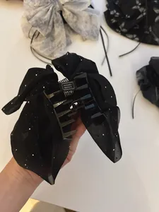 Detail of handmade black chiffon bow hair claw clip with silver glitter and inner label