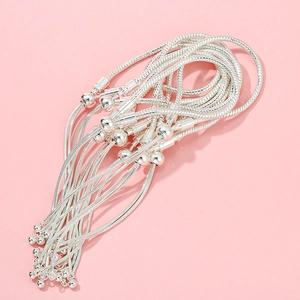 Detailed view of silver snake chain bracelets with round clasps on pink background