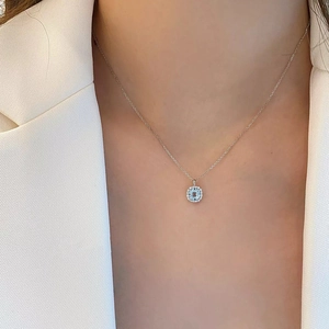 Detail of blue aquamarine halo pendant necklace on model with polished silver chain
