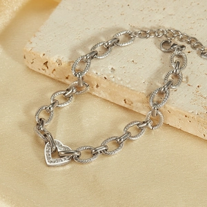 Macro detail of silver steel chain bracelet with heart charm and sparkling zircon stones