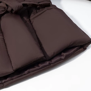 Detailed close-up of the hem and pockets on a dark brown oversized V-neck puffer jacket