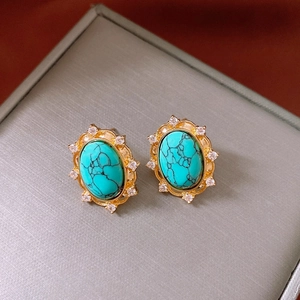 Close-up of vintage gold oval earrings with turquoise stone and zircon floral details