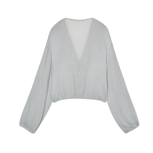 Detail of light grey V-neck long sleeve blouse with elegant ruffle trim and lantern sleeves