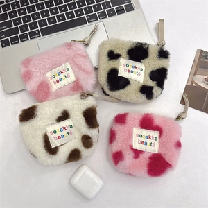 Mini plush cosmetic bags with leopard and cow prints next to a laptop and AirPods