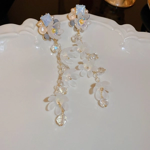 Detail of floral tassel earring with blue gemstones and pearls on a white porcelain tray