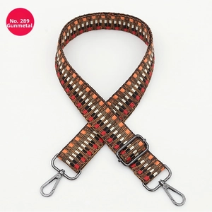 Detail of adjustable woven bag strap with geometric orange and red patterns and gunmetal clips