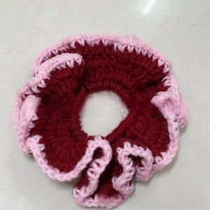 Detailed knit texture of a two-tone ruffle scrunchie in burgundy and pink yarn