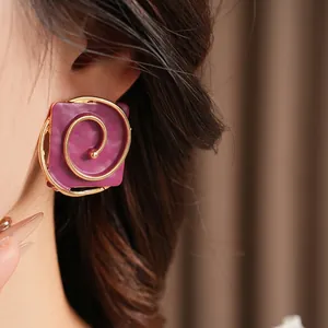 Vintage style square purple earrings with gold spiral design worn by model