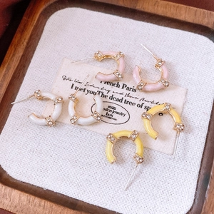 Three pairs of vintage C-shaped earrings with rhinestones in pink, white and yellow colors