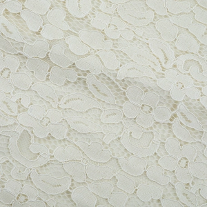 Macro detail of creamy lace fabric with intricate floral patterns and mesh structure