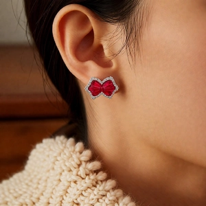 Detail of red zircon bow ear cuff with sparkling stones worn on model's ear