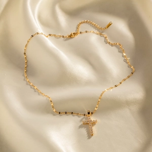 Detail of 18K gold stainless steel cross pendant with white zircon on silk background