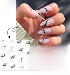 Detail of floral press-on nails with black and white flower patterns and tiny rhinestones