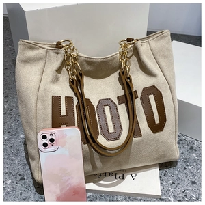 Detail view of large tote bag with mobile phone for size reference and metal chain